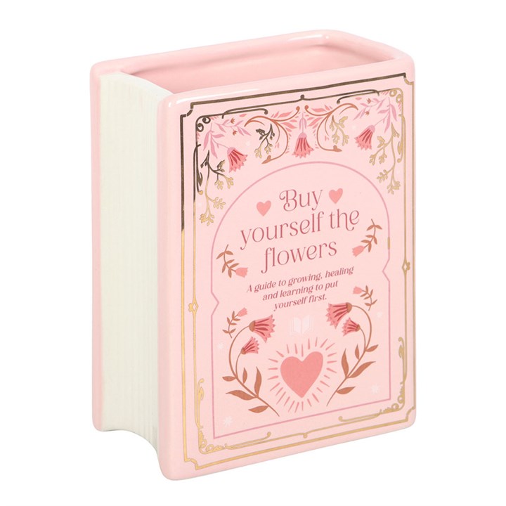 Pink book shaped vase with floral design and text on a white background