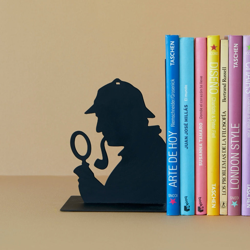 Bookend shaped like a silhouette of a detective with books stacked behind on a beige surface.