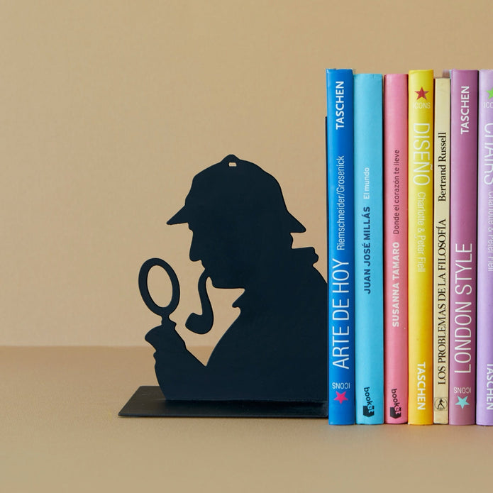 Bookend shaped like a silhouette of a detective with books stacked behind on a beige surface.