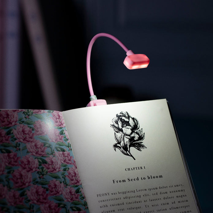 Pink LED reading light on an open book with floral design