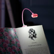 Pink LED reading light on an open book with floral design