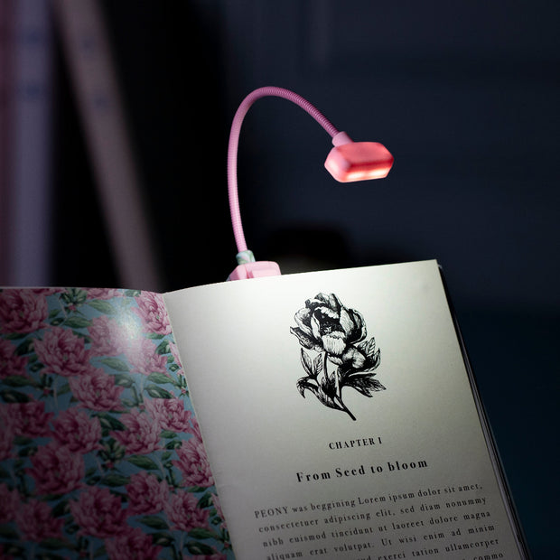 Pink LED reading light on an open book with floral design