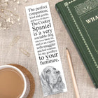 Bookmark with dog illustration and text on a table with a book and cup of coffee.