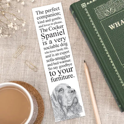Bookmark with dog illustration and text on a table with a book and cup of coffee.