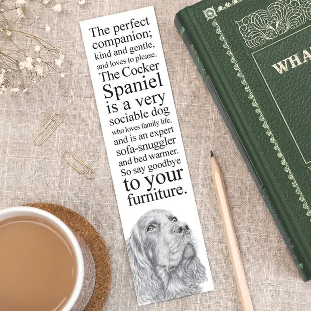 Bookmark with dog illustration and text on a table with a book and cup of coffee.