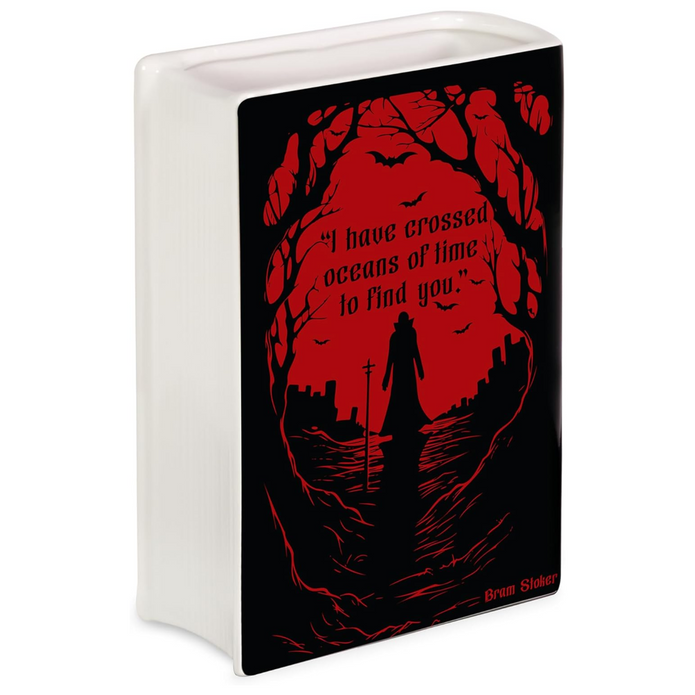 A ceramic book shaped vase with a printed black and red front panel featuring a gothic silhouette scene and the quote, 'I have crossed oceans of time to find you' by Bram Stoker.