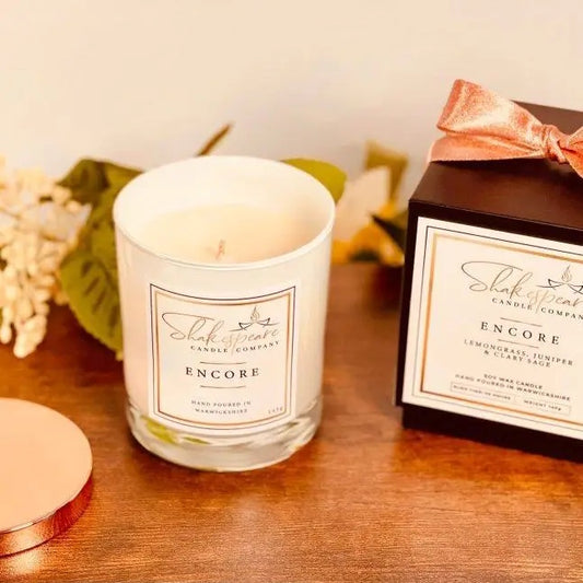 Shakespeare Candle Company candle and packaging on a wooden surface with decorative elements.