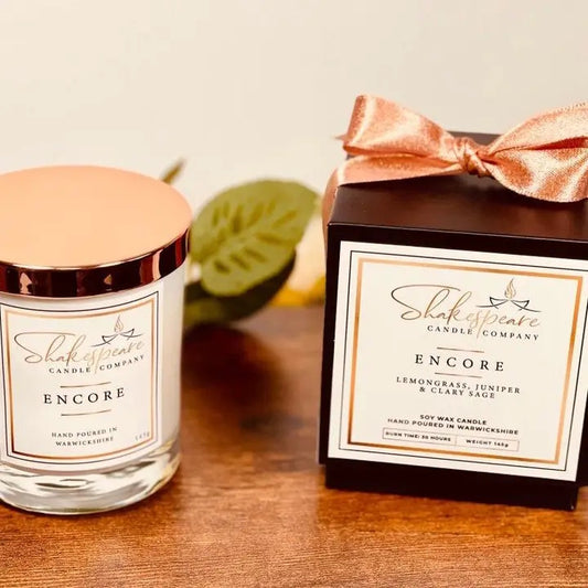 Shakespeare Candle Company candle and packaging on a wooden surface with a neutral background