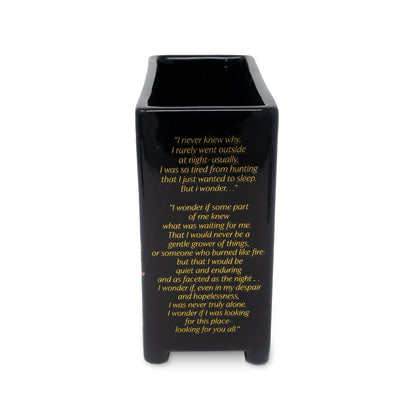 Black vase with yellow text on a white background