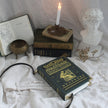 Decorative setup with a book, candle, and bust on a white surface