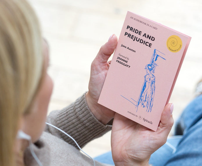 Person holding a pink book titled 'Pride and Prejudice' by Jane Austen.