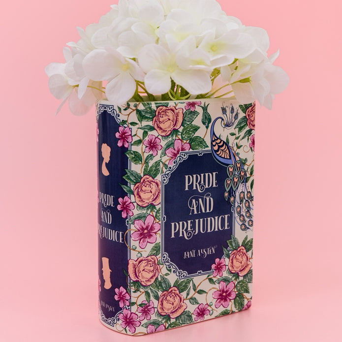 Decorative container with 'Pride and Prejudice' design filled with white flowers on a pink background