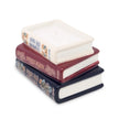 Stack of decorative books candle with visible titles on a white background