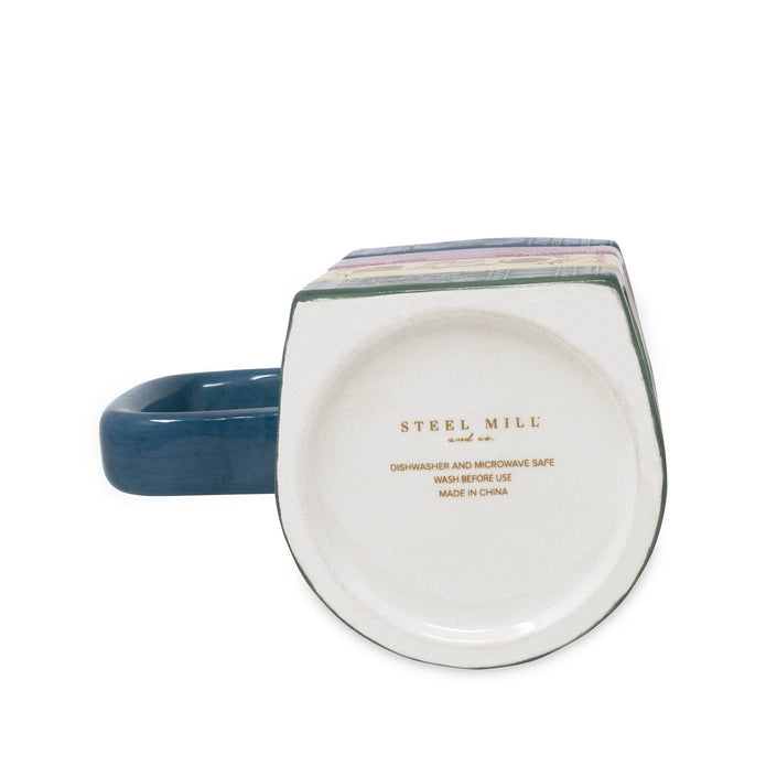 The bottom view of a ceramic mug with a dark blue handle and a white interior printed with the brand name 'STEEL MILL' in gold text.