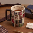 A ceramic mug filled with tea sits on a wooden table, decorated with a patchwork of vintage postage stamp designs in muted red, green, blue, and brown tones. The mug has a dark brown handle and the inside rim is printed with the text 'From Pemberley, with love'.