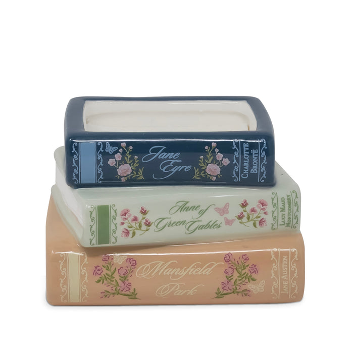 Three stacked ceramic book-shaped containers with floral designs and decorative spines, shown on a plain white background.