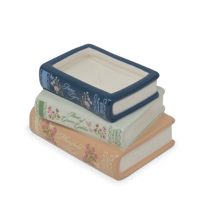 A decorative stack of three miniature books with floral designs and gold lettering, featuring a navy blue top book, a pale green middle book, and a peach-colored bottom book, on a white background.