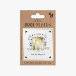Packaging of book plates with a gold 'm' design on a white background