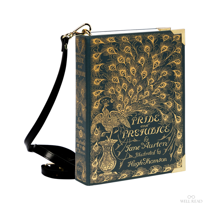 A book-shaped crossbody bag featuring the cover design of 'Pride and Prejudice'. The bag has a dark teal-blue background with gold peacock feather and text illustrations, a black leather strap, and gold metal corner protectors and hardware, shown on a plain white background.