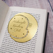 Gold 'Midnight Readers Club' bookmark on an open book