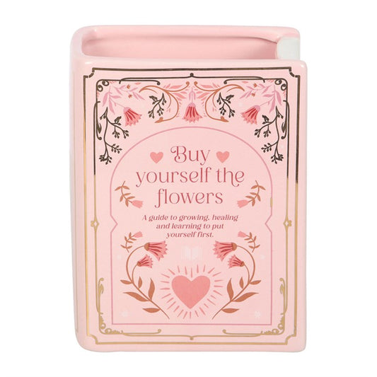 Pink book shaped vase with floral design and text on a white background