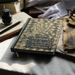 Vintage book titled 'Pride and Prejudice' by Jane Austen on a table with gloves and inkwell.