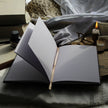 Open notebook on a textured surface with a candle and gloves in the background