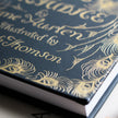 Book with gold calligraphy and decorative elements on a dark blue background