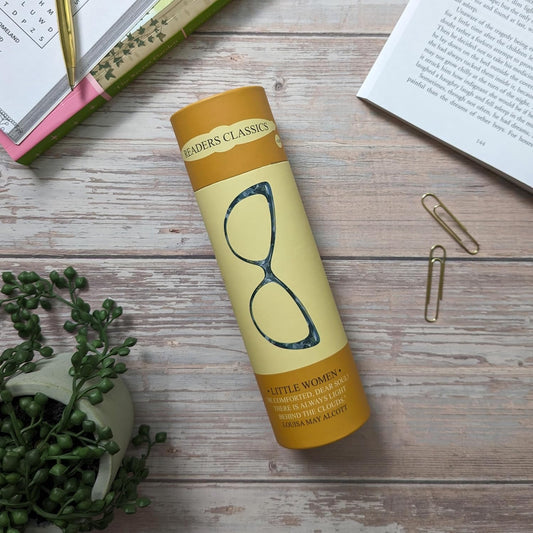 Yellow penguin book style tube with 'Little Women' on a wooden surface with books and a plant.