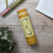 Yellow penguin book style tube with 'Little Women' on a wooden surface with books and a plant.