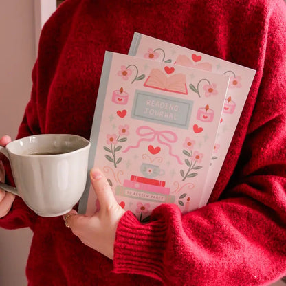 Person holding a cup and a 'Reading Journal' with decorative cover