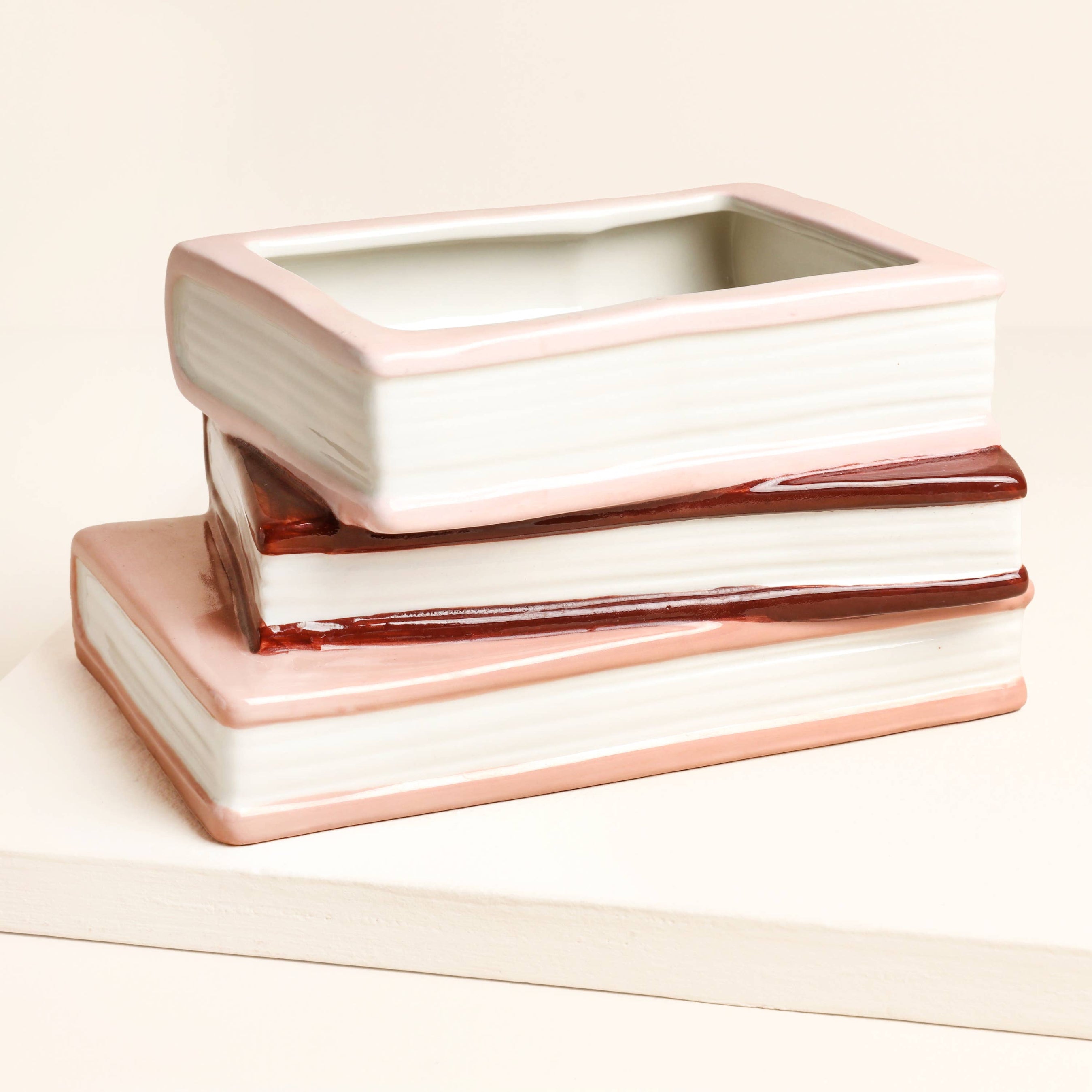 Stack of ceramic containers with rose gold accents on a light background