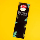 Cartoon mushroom on a black bookmark saying stop talking I'm reading on a yellow background