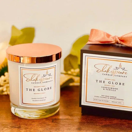 Shakespeare Candle Company candle and packaging on a wooden surface with leaves in the background