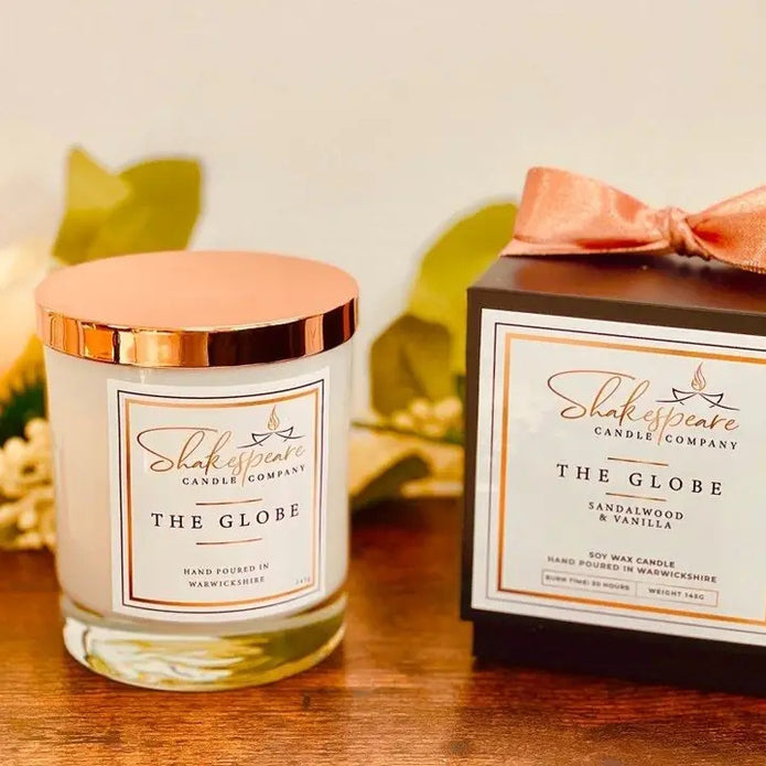 Shakespeare Candle Company candle and packaging on a wooden surface with leaves in the background