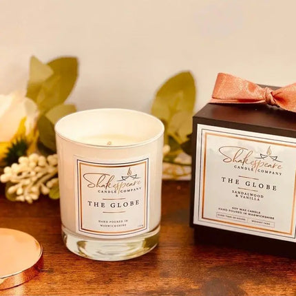 Shakespeare Candle Company candle and packaging on a wooden surface with decorative elements.