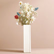 White vase with dried flowers on a beige background