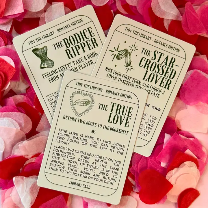 Three book-themed cards on a bed of pink and red flower petals.
