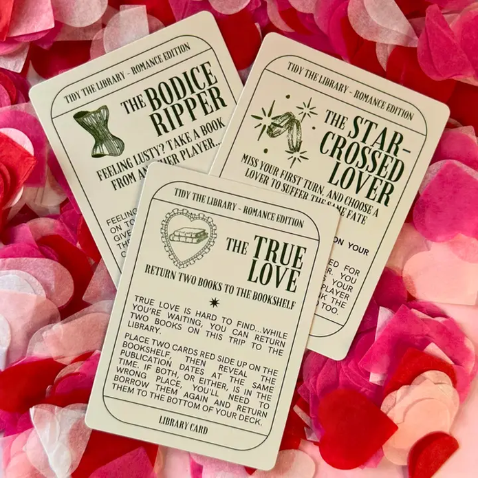 Three book-themed cards on a bed of pink and red flower petals.