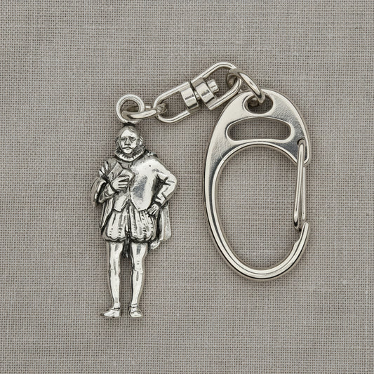 A silver-tone metal keychain featuring a detailed miniature figure of a historical man in Renaissance clothing, attached to a carabiner clip, displayed on a bright blue satin fabric background.